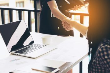 two people introducing themselves with a handshake before sitting together at a table