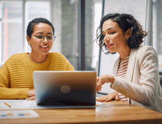 Lady using a laptop to train another lady. 