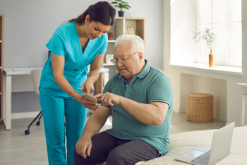 Care home nurse helping an elderly man with his mobile phone