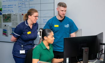 NHS clinicians around a computer station.
