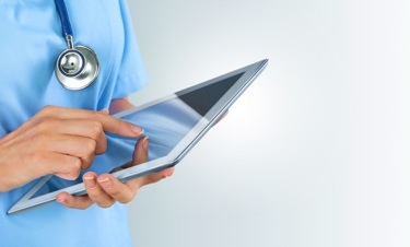A nurse using a tablet device to check patient data.