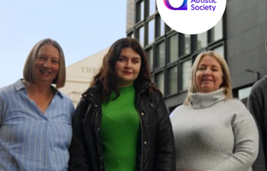 Three charity volunteer stood outside glass building