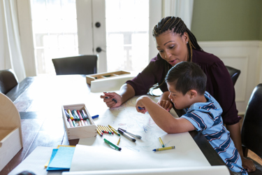 A black woman sitting with a young child helping with their homework