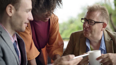 Two white men and a black woman smiling with each other 