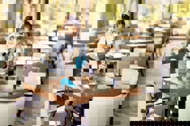 Female waitress wearing face mask cleaning tables