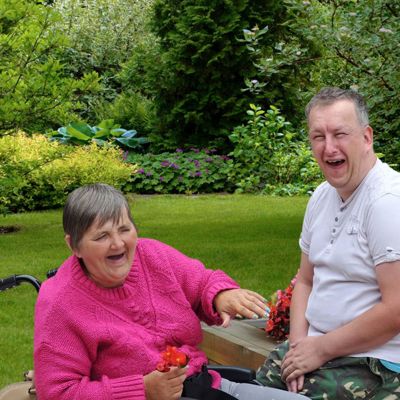 A white woman in a wheelchair smiling with a white man
