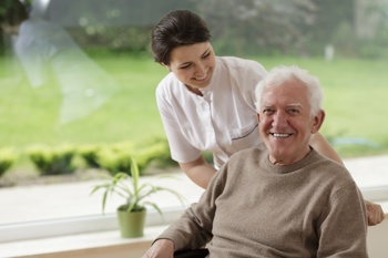 A carer smiling at an elderly man. 