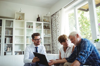 An elderly couple discussing information with a smartly dressed man.
