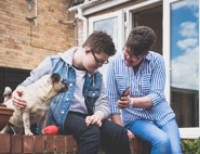 A woman showing a care planner app on her phone to a boy who is stroking his dog