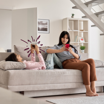 Mother and daughter on sofa looking at their phones