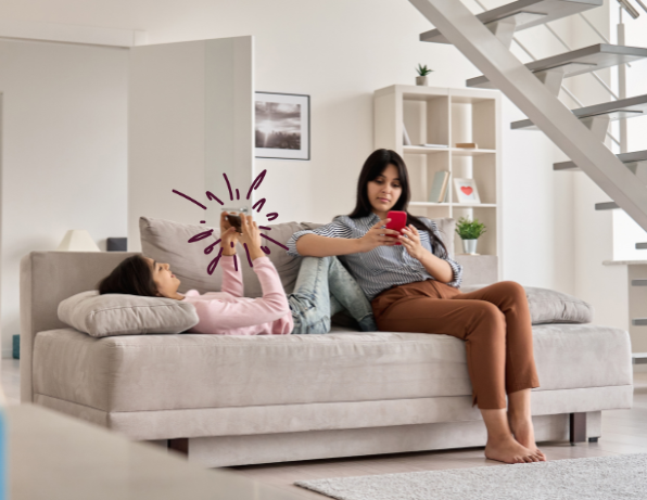 Mother and daughter on sofa looking at their phones