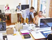 People working and collaborating at desktop computers in an open-plan office