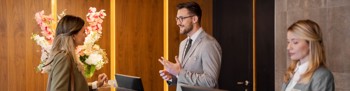 Two hotel staff, one speaking with a guest