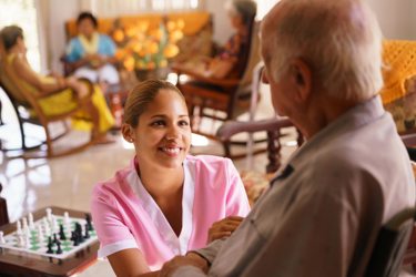 care worker smiling while checking on an elderly resident