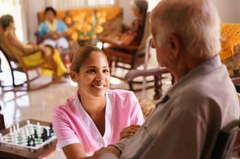 care worker smiling while checking on an elderly resident