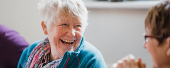 2 elderly ladies smiling at each other