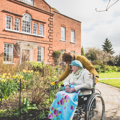 A lady pushing an eldery woman in her wheelchair 
