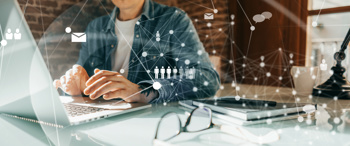 Person working on a laptop at a desk, overlaid with digital network graphics representing communication and data connections.