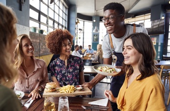 A waiter serving food to a table of customers 