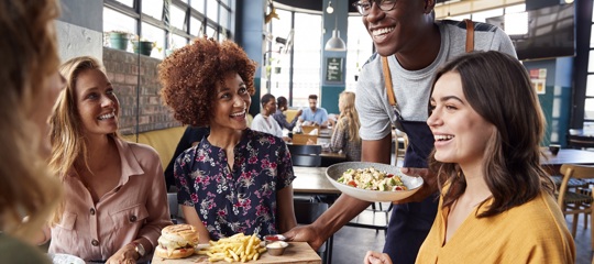 A waiter serving food to a table of customers 