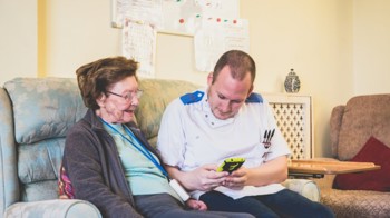 carer showing elder woman technology