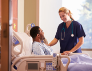 A man laying on a hospital bed being comforted by a nurse