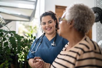 nurse holding elderly lady's hand