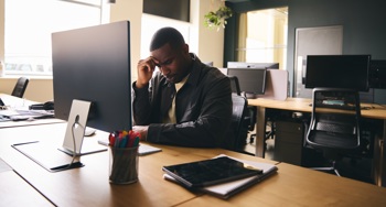 A student visibly struggling with their mental health at a desk.