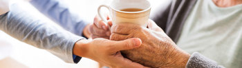carer handing resident a cup of tea