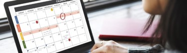 A lady looking at a digital calendar on a laptop.