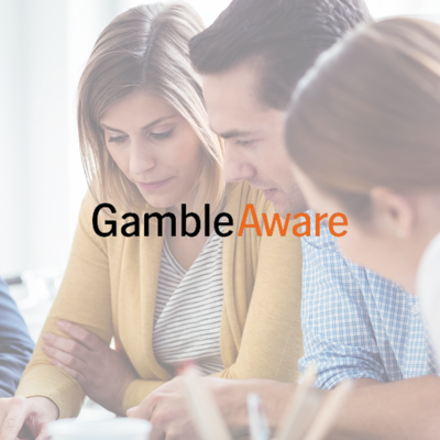 Three people sitting together and looking at documents, with the Gamble Aware logo overlaid on the image