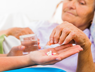 carer helping elderly resident take her medicine