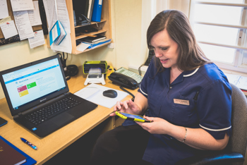 A female carer sat at her desk using a mobile phone.