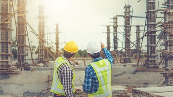 two construction workers pointing to something in front of them