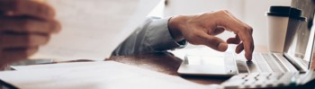 A man typing out something off of a piece of paper.