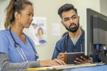 2 healthcare workers looking at a computer screen.