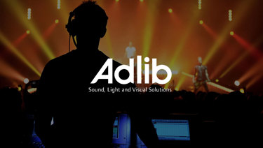 Silhouetted technician at a control panel during a live event, with ‘Adlib Sound, Light and Visual Solutions’ logo