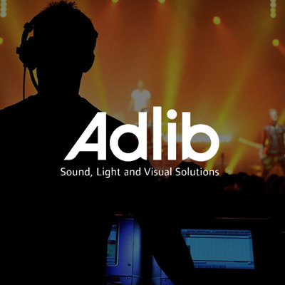 Silhouetted technician at a control panel during a live event, with ‘Adlib Sound, Light and Visual Solutions’ logo