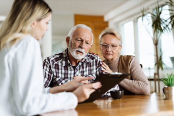A lady going through paperwork with an elderly couple.