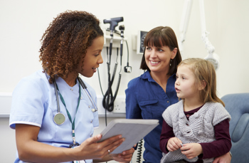 A woman with a child on her lap talking to a nurse 