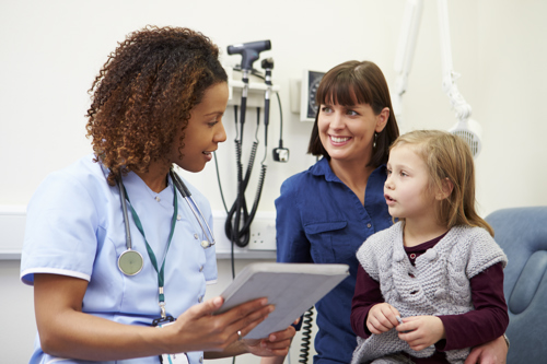 A woman with a child on her lap talking to a nurse 