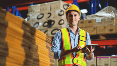 Image of a worker in a warehouse wearing safety gear doing stock take