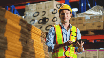 Image of a worker in a warehouse wearing safety gear doing stock take