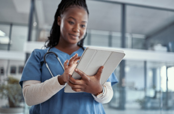 A black female nurse looking at an electronic tablet 