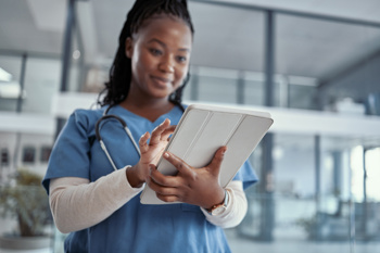 A black female nurse looking at an electronic tablet 