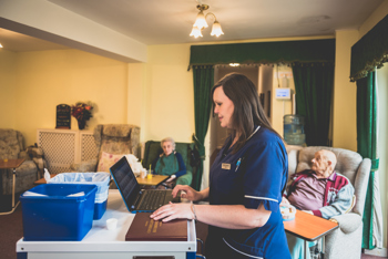 A carer sat at her desk on a laptop