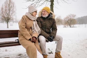 elderly couple sitting together on a bench during winter