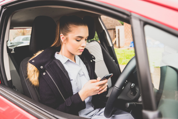 A carer on her phone in a parked car