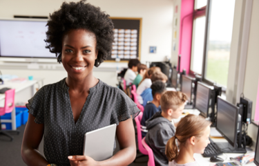 School teacher smiling in front of class room