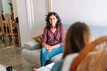 A woman sitting down with another woman smiling